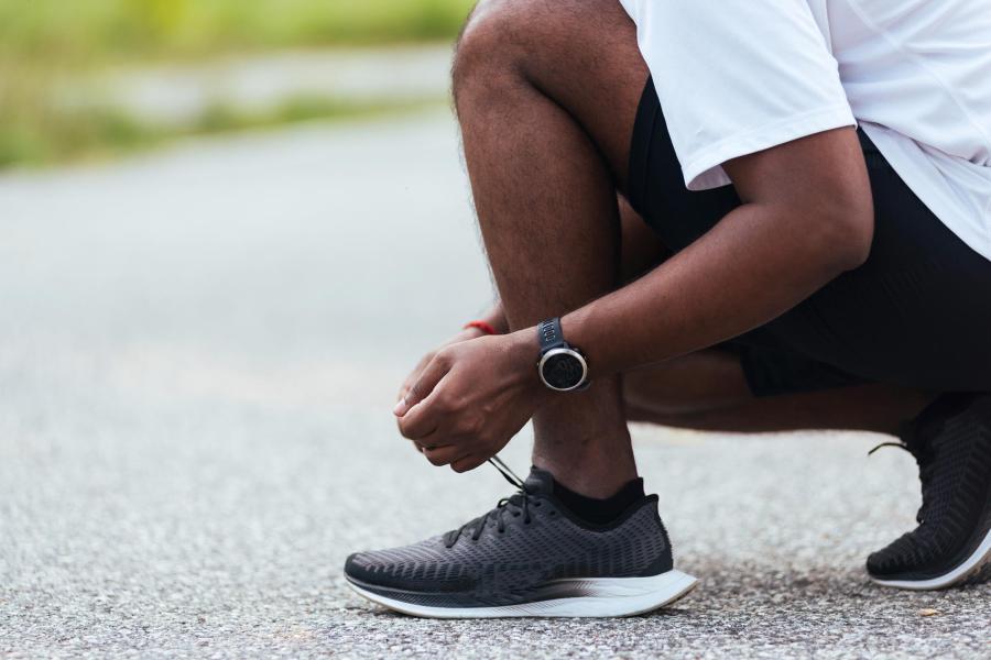 Someone stooping to tie their shoe before running