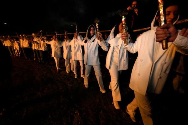 Iranian Zoroastrian youths join hands after setting a prepared pile of wood on fire