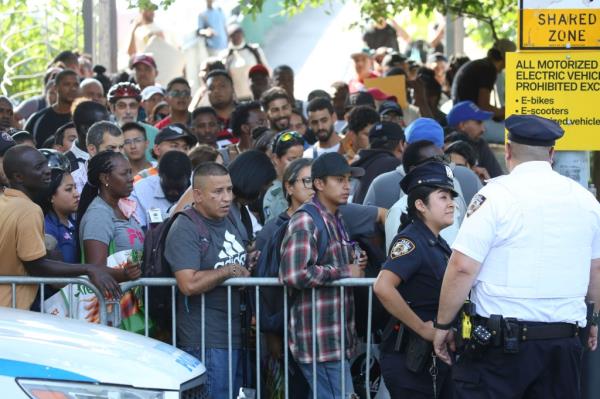 NYPD, NYC Parks, and Randall's Island Alliance clearing a camp of dozens of tents and about a hundred migrants near Ward's Island pedestrian bridge, with migrants waiting to return to city-run shelter.