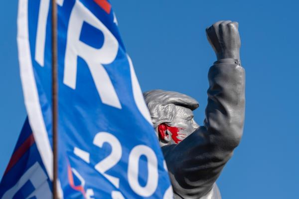 Statue of former President Donald Trump on a truck at the Butler Farm Show, fist raised in front of a flag