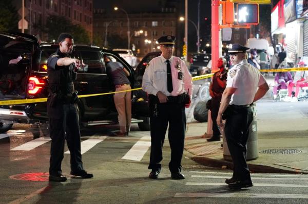 Three NYPD officers at the cordoned off crime scene discuss the shooting.