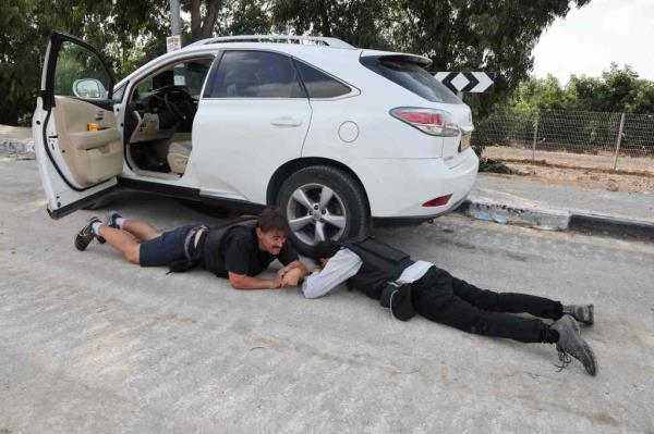 Israeli journalists hide behind a car during a rocket attack.