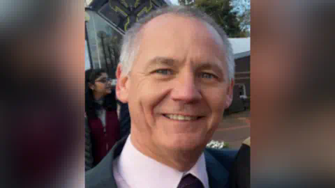 Cumbria Police handout A headshot of Paul Taylor. He is wearing a pink shirt and tie.