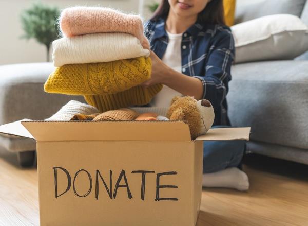 A woman adds clothing to a donation box