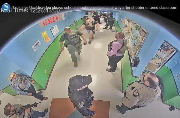 In this photo from surveillance video provided by the Uvalde Consolidated Independent School District via the Austin American-Statesman, authorities stage in a hallway as they respond to the shooting at Robb Elementary School in Uvalde, Texas, May 24, 2022