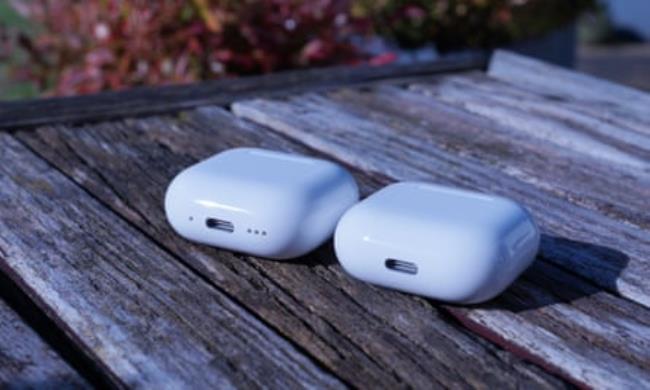 The cases for the Apple AirPods 4 and AirPods 4 with ANC on a wooden table.