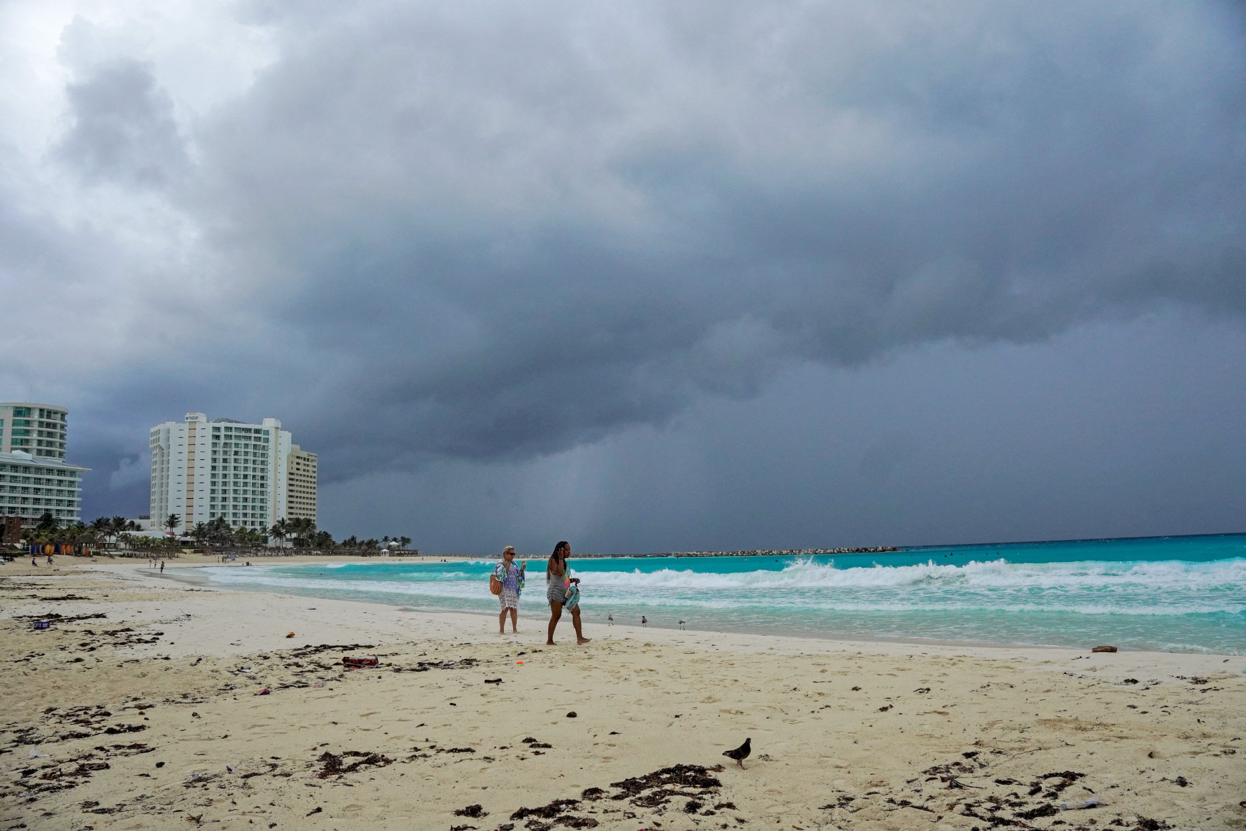 Storm clouds are pictured as people walk on the beach ahead of the arrival of Hurricane Helene in Cancun, Quintana Roo state, Mexico, on Tuesday
