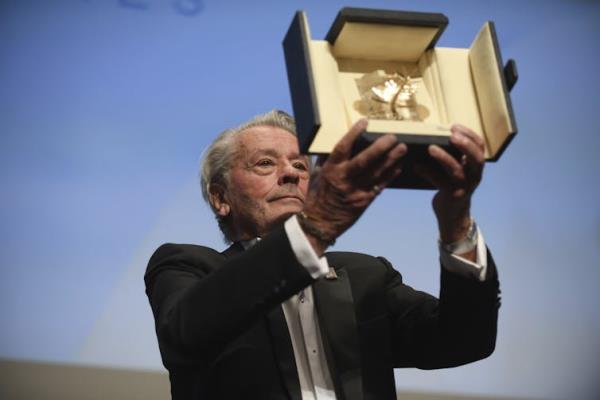 Delon holds his award aloft.