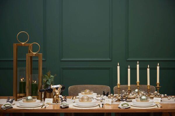  Adding height to the Christmas dining table with a candelabra (candle tray holder €59) and hurricane lamps (Thorpe from €89) from Meadows & Byrne gives a wow finish.