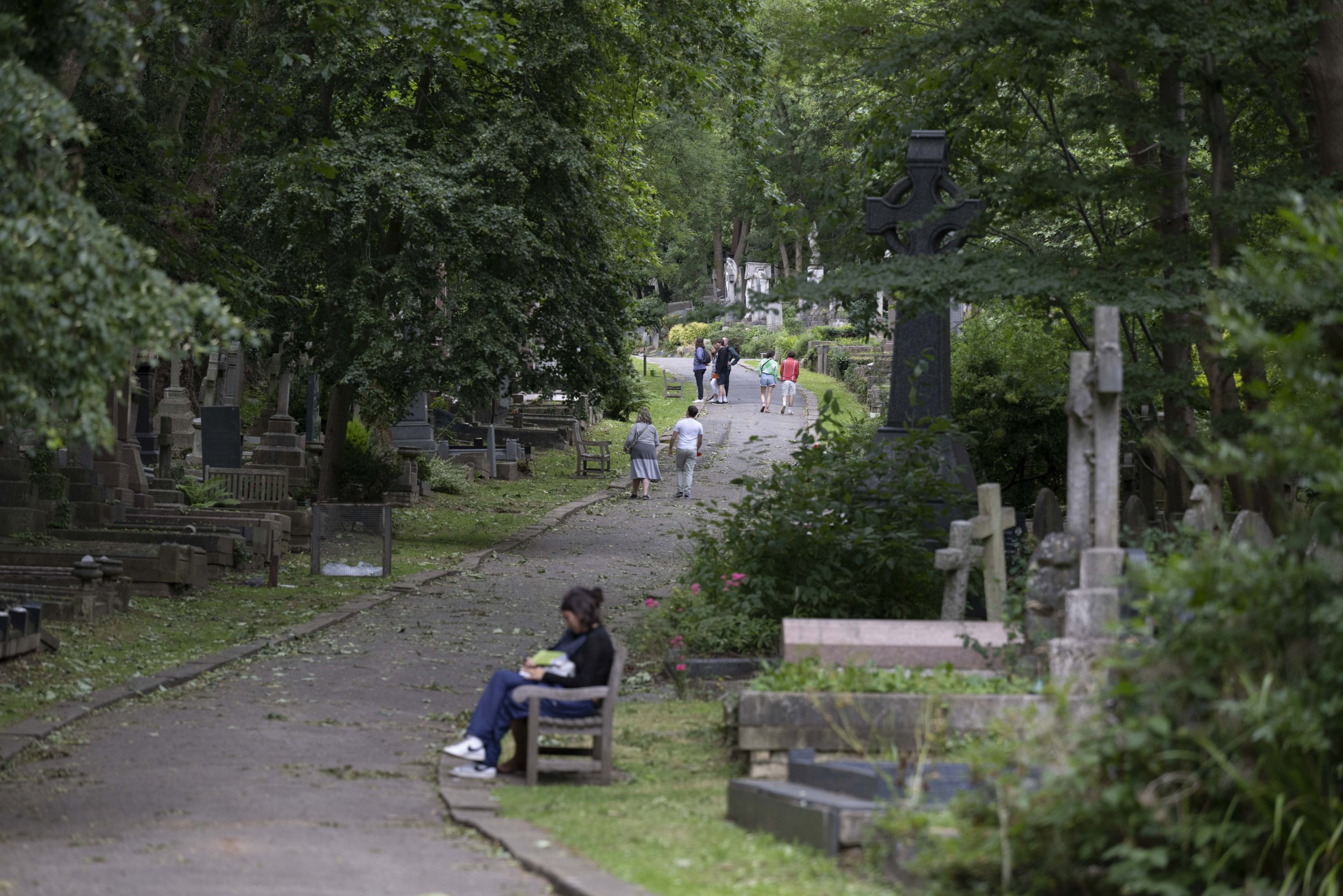 A view of tombstones as people walk at the London Highgate Cemetery