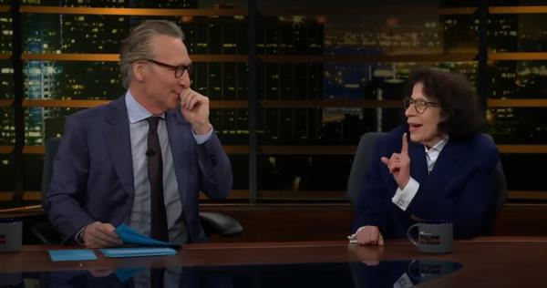 Bill Maher and Fran Lebowitz sitting at a desk during a panel discussion on Real Time with Bill Maher, with Lebowitz gesturing during her points.