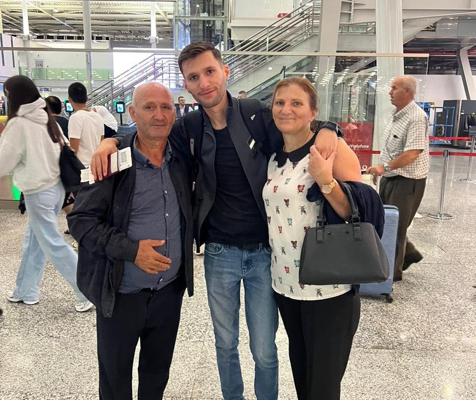 Gezim at the airport with his parents, both looking proud and tearful