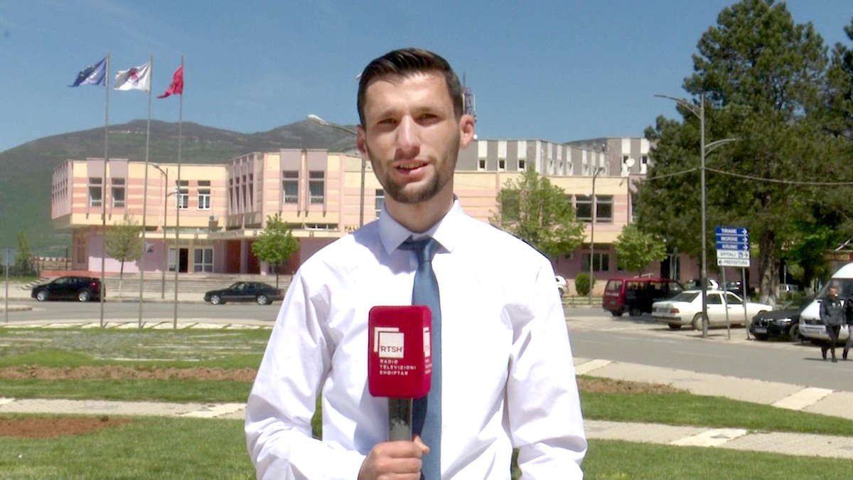 Gezim holding a microphone as a broadcaster on TV in Albania