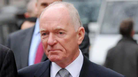 PA Media John Macnamara, wearing a suit, tie and a wool coat, pictured outside the High Court in 2008