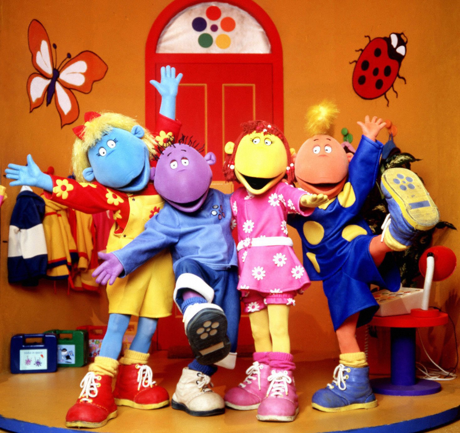 Tweenies characters Bella, Milo, Fizz and Jake outside a red front door