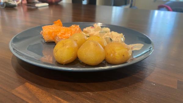 Image shows a plate with boiled potatoes, salmon and salad