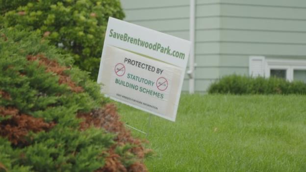 A sign on a lawn that reads Save Brentwood Park dot com. Protected by Statutory Building Schemes. Two red circles with a line through the words Bill 44 and Bill 47.