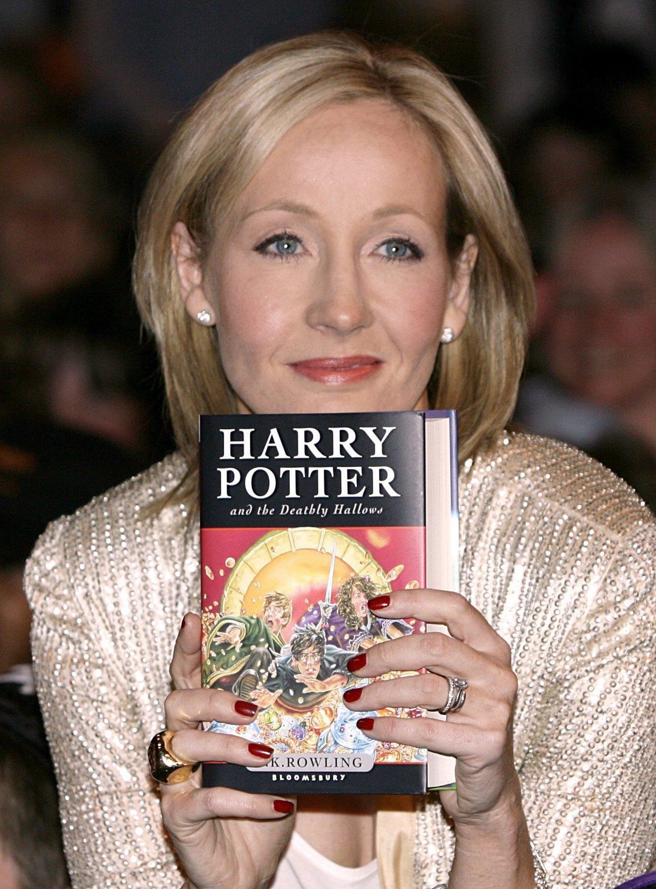 JK Rowling holding a copy of Harry Potter and the Deathly Hallows