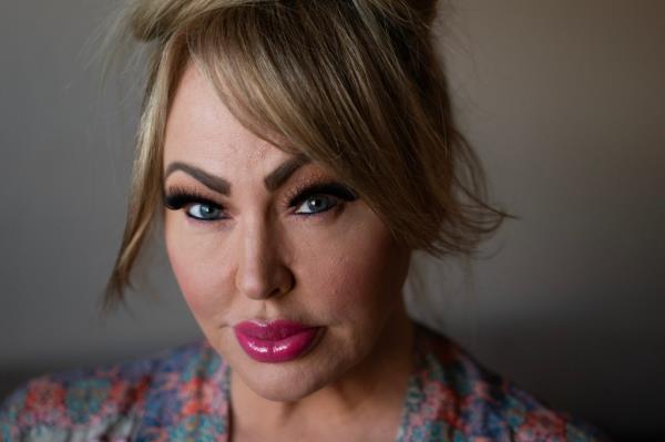 Rachel Kennedy posing in her house in Yuma, Arizona, a woman with her hair done up and makeup applied.