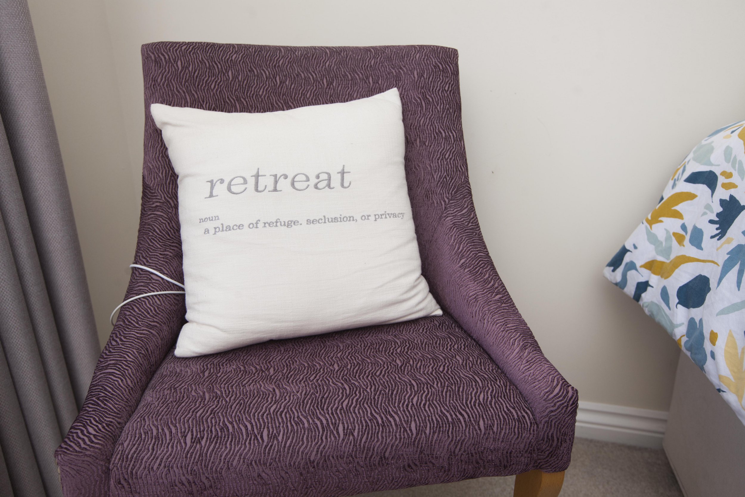 Gill Ross and her apartment in Bagshot, Surrey are the subject of a What I Own feature. This picture shows a cushion bearing the definition of the word 'Retreat' on a chair in the bedroom.