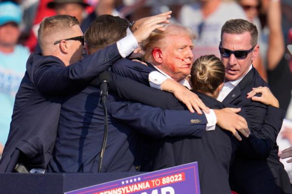 Donald Trump is surrounded by U.S. Secret Service agents as he is helped off the stage at a campaign rally in Butler, Pa., July 13, 2024. 