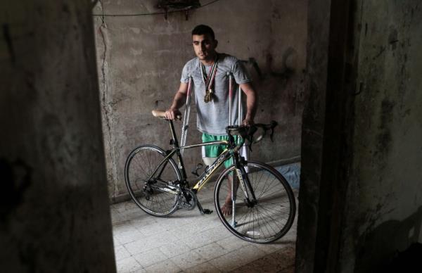 Palestinian cyclist Alaa Al-Daly, 21, who lost his leg by a bullet fired by Israeli troops along the Gaza border during a protest, stands next to his bicycle, at his home in Rafah in the southern Gaza Strip on April 19, 2018. Daly's dream of competing for Palestine at the Asian Games has been shattered after the athletes right leg was amputated after being shot by Israeli soldiers during recent demonstrations in Gaza. (Photo by SAID KHATIB / AFP)