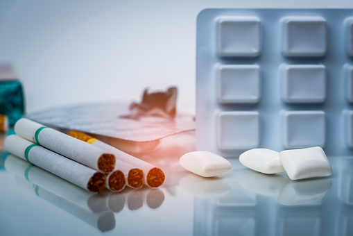 Nicotine chewing gum in blister pack near pile of cigarette