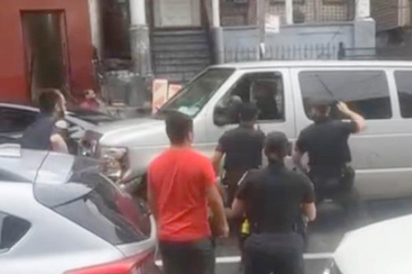 Cops and a pedestrian surrounding a stolen van in the Bronx