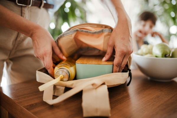 A woman's hands seen putting lunch in a bag.