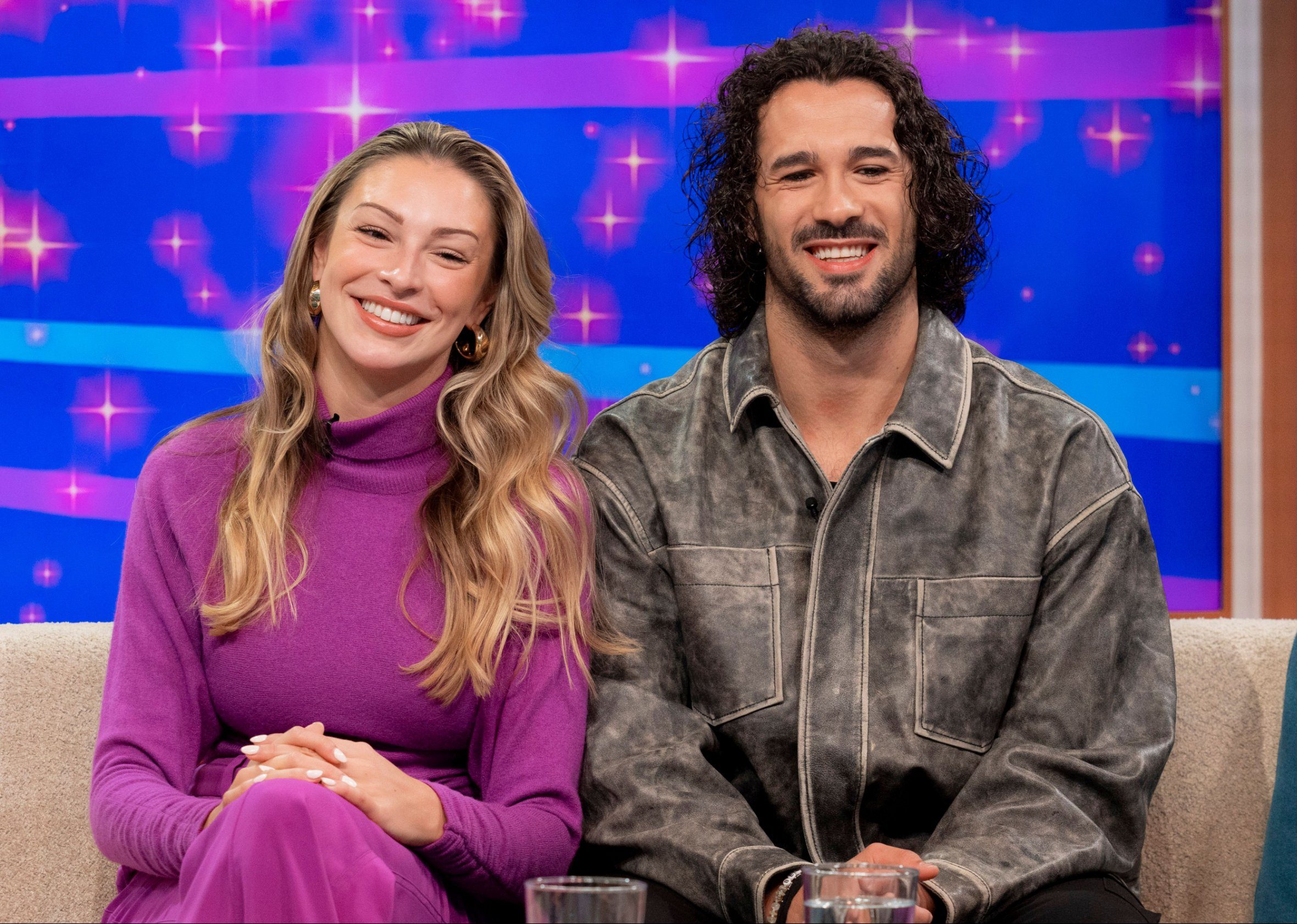 Zara McDermott and Graziano Di Prima smiling while sitting next to each other during a TV appearance