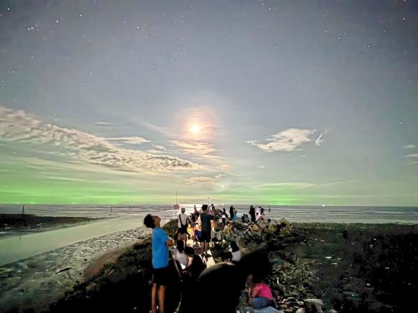 People waiting to see the Perseid meteor shower, but the bright moon and green glow of the squid fishing boats on the horizon caused light pollution.