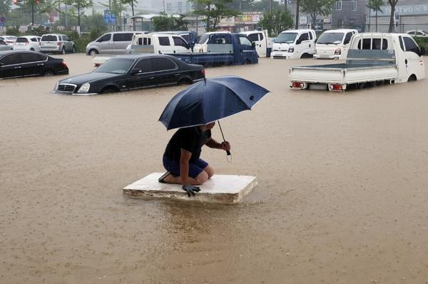 Workers commute through streets flooded by heavy rain in downtown Seokhyun-dong, Mokpo, South Jeolla Province on Monday morning.