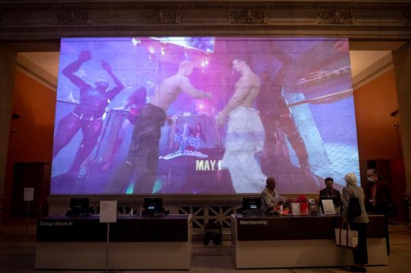 Screen behind Met ticket counter showing images from "Metta Prayer"