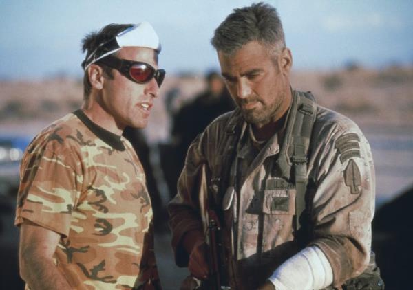 George Clooney in camouflage and sunglasses speaking with director David O. Russell on the set of the film 'Three Kings'