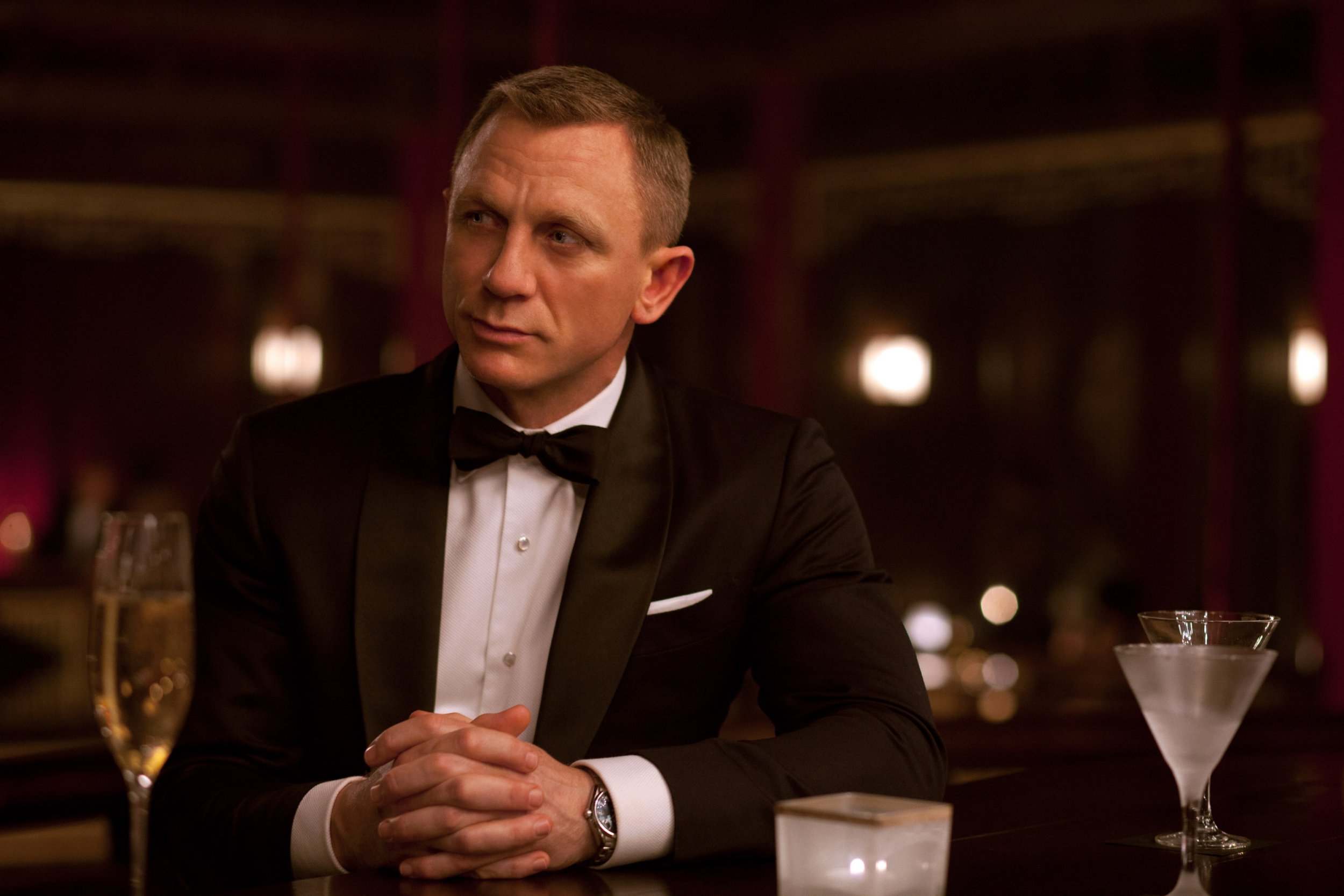 Daniel Craig as James Bond sits at a bar in a tuxedo in a still from the film Skyfall