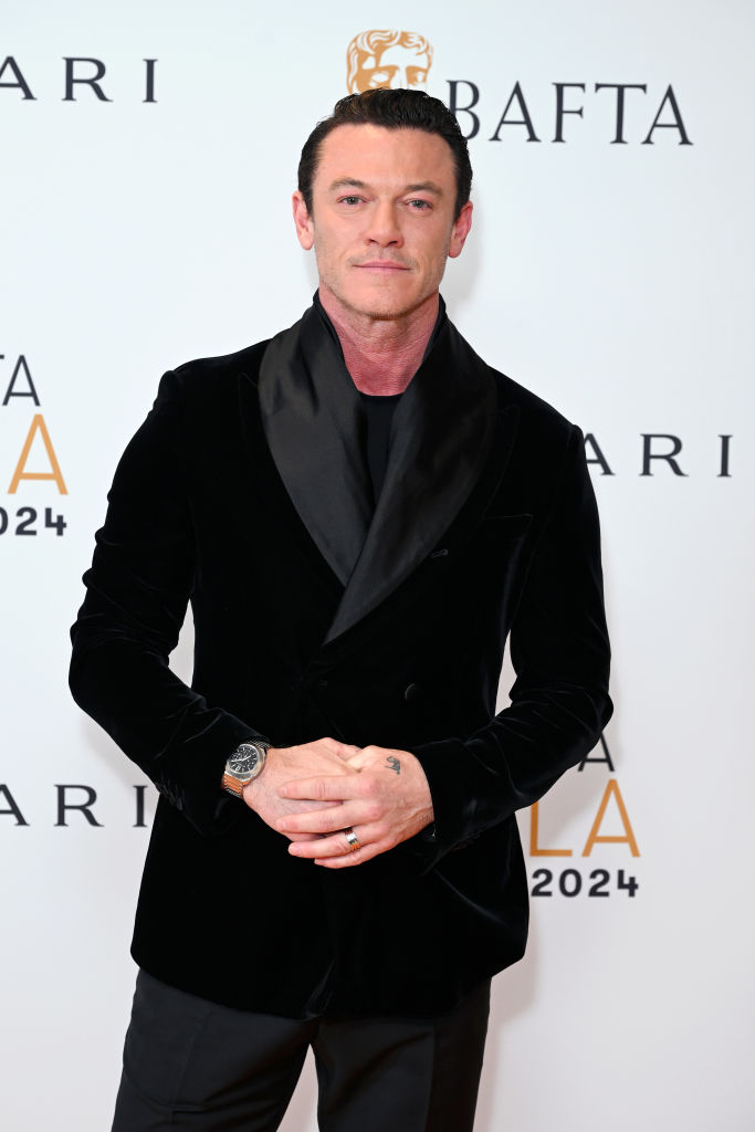 Luke Evans poses in a black velvet suit with statement lapels on the red carpet of the 2024 Baftas