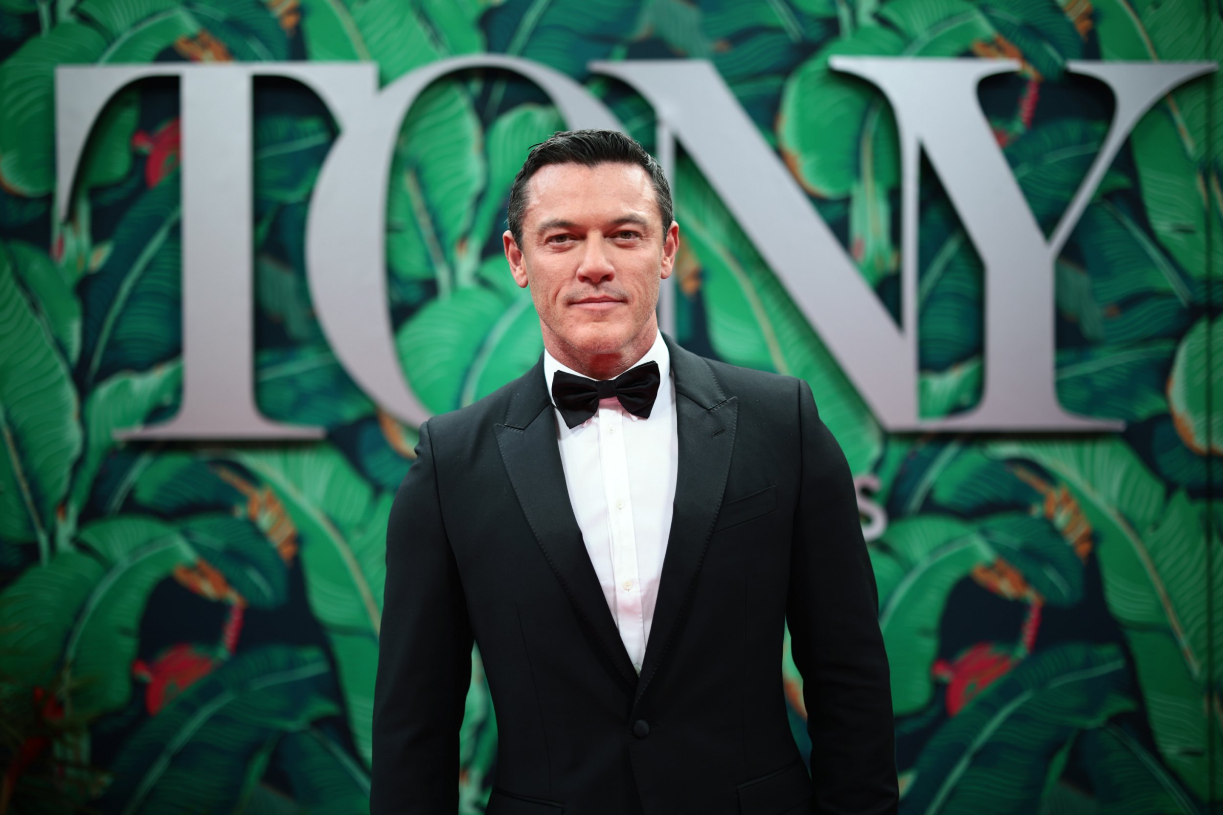 Luke Evans poses in a classic tuxedo on the red carpet at the 2023 Tony Awards