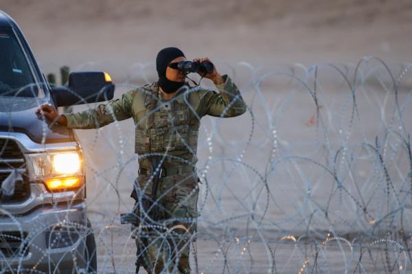 A member of the Texas National Guard stands guard with the purpose of inhibiting the crossing of migrants to the United States on the banks of the Rio Bravo river, the border between Mexico and the United States