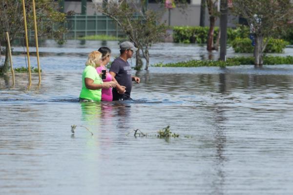 People walk in the water as the streets are flooded in the Southeast Seminole Heights section of Tampa due to Hurricane Milton on October 10, 2024 in Florida.