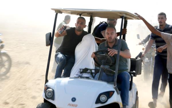Palestinians transport a captured Israeli civilian from Kibbutz Kfar Azza into the Gaza Strip on Saturday, Oct. 7, 2023.