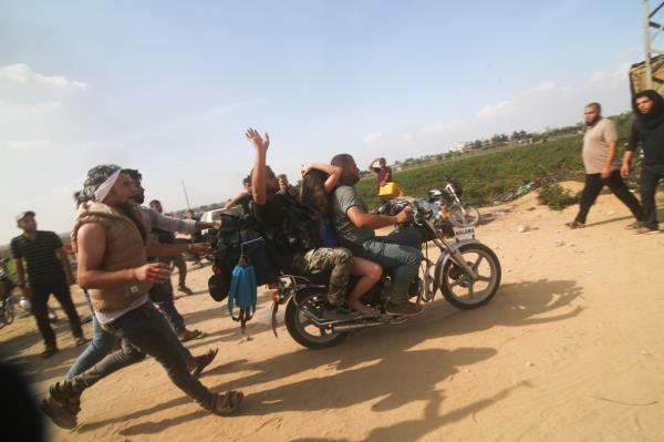 Palestinians transport a captured Israeli civilian, center, from Kibbutz Kfar Azza into the Gaza Strip on Saturday, Oct. 7, 2023.