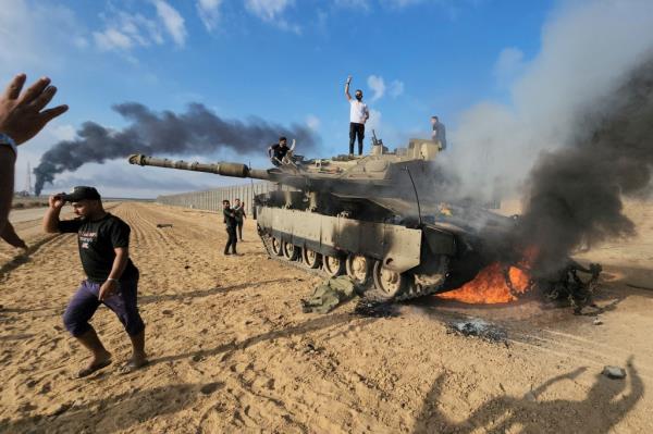 Palestinians celebrating on a destroyed Israeli tank in the Gaza Strip on October 7, 2023.