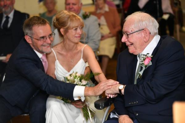 Richard and Fiona hold the hand of Fiona's father, Henry 