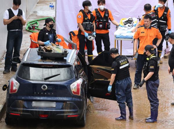 A submerged sedan is being carried by rescue workers as part of the underpass drainage work in Cheongju, North Chungcheong Province, on Monday. (Yonhap)