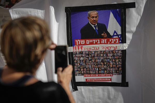 A woman takes a photo of a poster showing Israelis held captive in Gaza plastered underneath a picture of Benjamin Netanyahu in Tel Aviv. Picture: AP Photo/Ariel Schalit A woman takes a photo of a poster showing Israelis held captive in Gaza plastered underneath a picture of Benjamin Netanyahu in Tel Aviv. Picture: AP Photo/Ariel Schalit