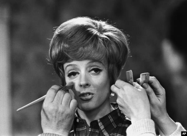 FILE - Make up and hair artists add the finishing touches to British actress Maggie Smith before she faces the camera with Peter Ustinov in the comedy 'Hot Millions' being filmed at Elstree Studios, England, Jan. 12, 1968.