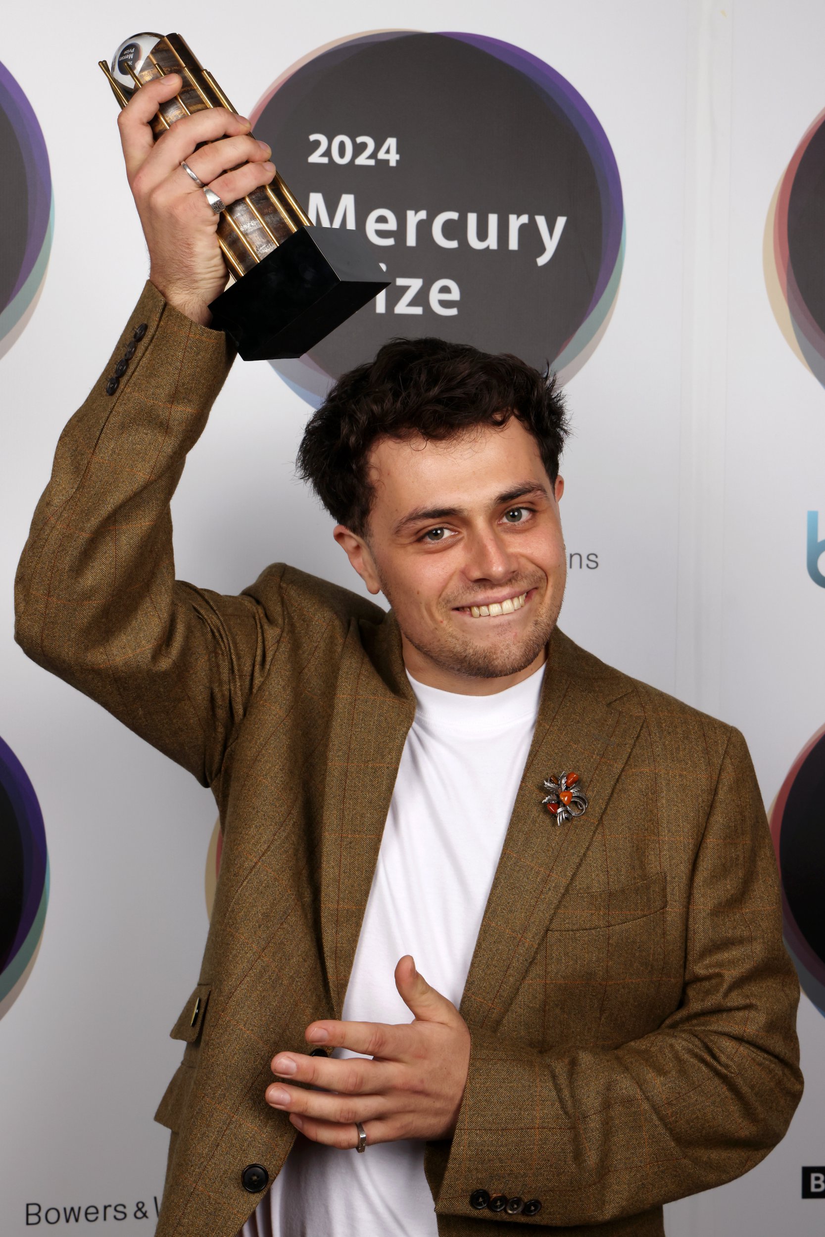 Corto.alto holds the Mercury Music Award above his head as he smiles at awards ceremony 2024