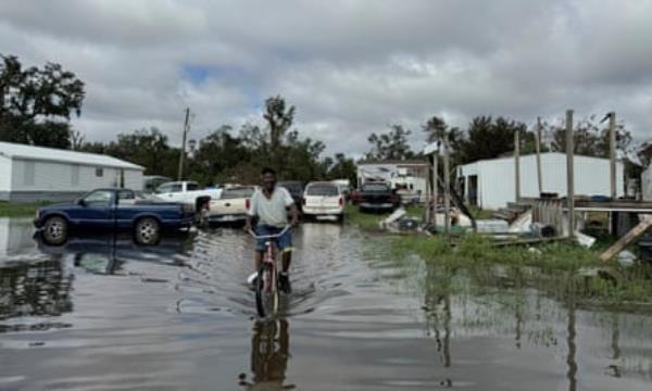 a man rides his bike through flooding 