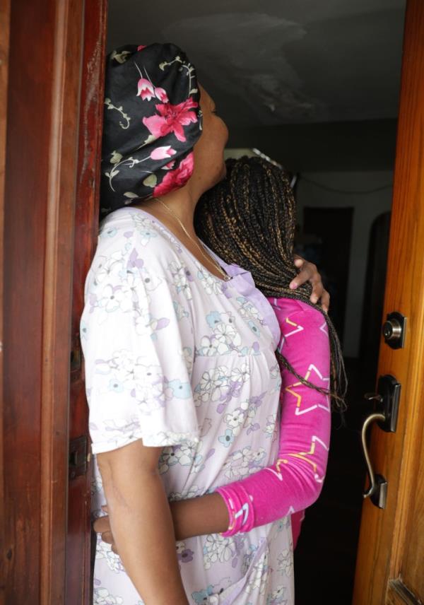 The aunt and niece hug in doorway.