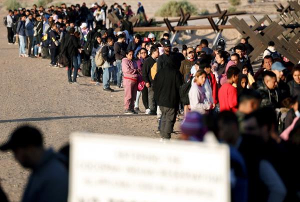 Migrants crossing the US-Mexico border at the Rio Grande, through concertina wire